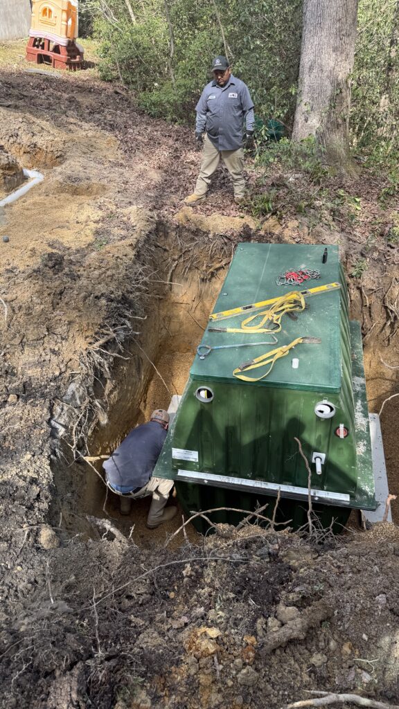 Technician installing a green BAT wastewater treatment unit