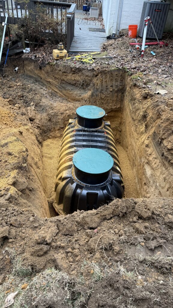 Plastic septic tank positioned in a gravel-lined residential excavation