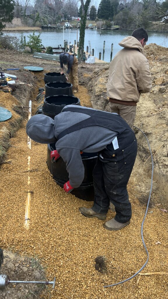 Crew installing septic system components in a gravel-lined excavation